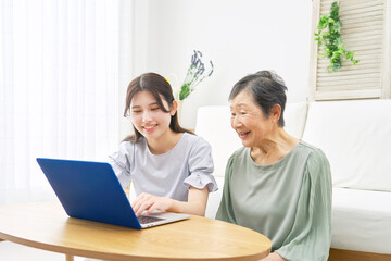 リビングでパソコンを使う孫と祖母