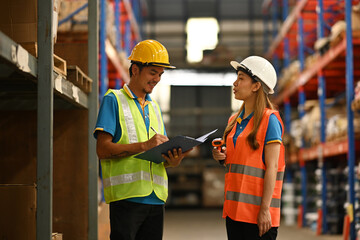 Warehouse worker standing between tall shelves full of shelves with good and discussing work together