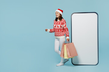 Full body young merry woman wear red sweater Santa hat posing big huge blank screen mobile cell...