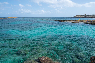 The beautiful Ognina beach in Syracuse with turquoise and green water and a small island in front of it
