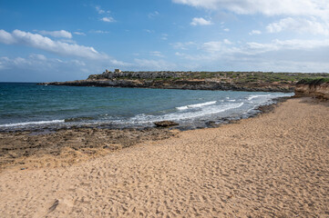 The beautiful Ognina beach in Syracuse with turquoise and green water and a small island in front of it
