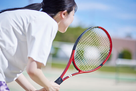 テニスコートでテニスをする若い日本人女性