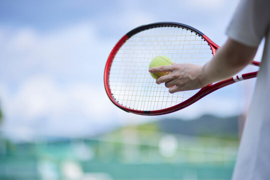 テニスコートでテニスをする若い日本人女性