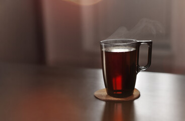 Green cup with hot tea in the sunlight. Lifestyle domestic photo concept. Minimalistic composition with copy space for text. Breakfast time with tasty warm drink