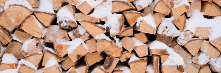 getextureerde brandhout achtergrond gehakt hout voor aanmaakhout en verwarming. houtstapel gestapeld brandhout berk bedekt verse ijzige bevroren sneeuw en sneeuwvlokken. koud weer en besneeuwde wintertijd. banier