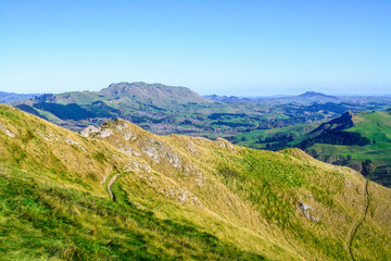 Narrow trail along a mountain ridge. Vast green valley and distand green peaks. Beautiful summer mountain landscape. A panoramic view of Te Mata Hills iin Hawke's Bay, New Zealand