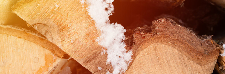 textured firewood background chopped wood for kindling. woodpile stacked firewood birch tree covered fresh icy frozen snow and snowflakes. cold weather and snowy winter time season. banner. flare