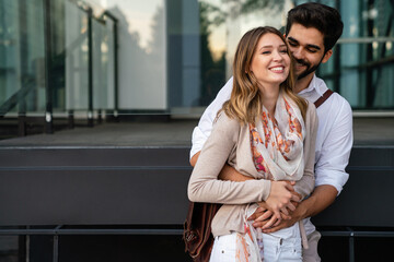 Close up of a smiling beautiful young couple embracing while standing outdoors.
