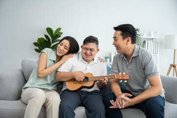 Asian attractive family playing with down syndrome son in living room.