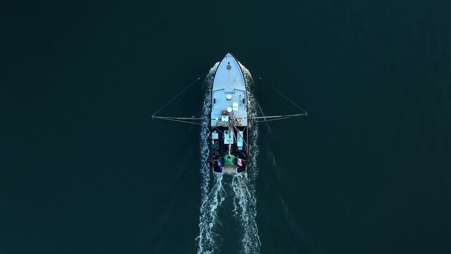 Top down aerial of fishing boat in America. Lobstermen on fishing vessel with USA flag waving in breeze.
