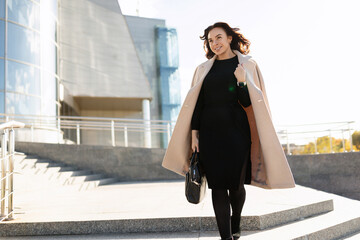 Obraz premium Businesswoman in stylish clothes walks up the steps of the office, career growth concept