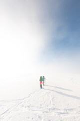 two girls with a backpack and snowshoes walk in the snow during a snow storm.