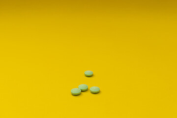 Green pills on a yellow background