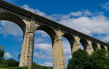 View of the structure of a stone bridge with perspective view in the French town of Dinan, with blue sky and white clouds.