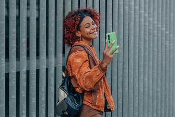 black latin american woman with mobile phone in the street