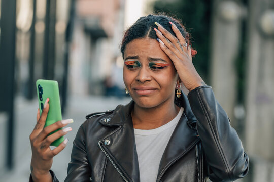 Woman With Mobile Phone In The Street And Expression Of Resignation