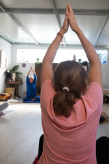 Fototapeta premium the woman in the pink T-shirt stretches her arms as she attends to her yoga teacher.