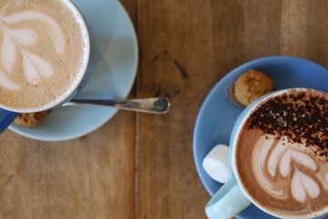 Two cups of coffee with spoon. Chai latte, hot chocolate in a mug. Latte art with a heart. Hot drinks for breakfast.