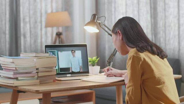 Side View Of A Young Female Looking At A Male Teacher Teaching On A Laptop While Studying At Home
