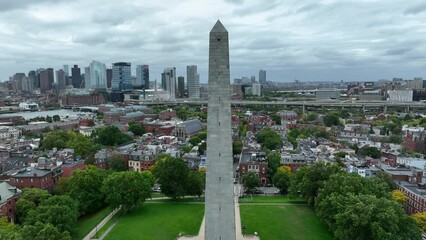 Rising aerial of Boston downtown skyline. Bunker Hill Monument and Zakim Bridge on cloudy day.