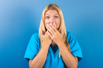Young blonde girl nurse scared covering her mouth with her hands. Concept fear.