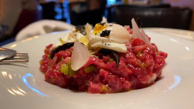 Delicious tuna tartare with little quail poached eggs, truffle and onions in Spain, gourmet tapas starter in a restaurant, 4K shot