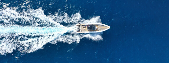 Aerial drone top down ultra wide photo with copy space of inflatable speed boat with wooden deck...