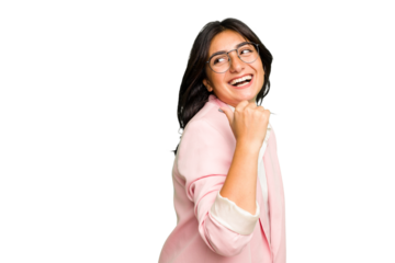 Young Indian business woman wearing a pink suit isolated points with thumb finger away, laughing and carefree.