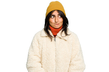 Young Indian woman wearing winter jacket and a wool cap isolated confused, feels doubtful and unsure.