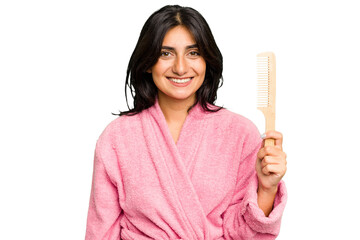 Young woman in a bathrobe holding an hair comb isolated happy, smiling and cheerful.