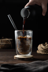 Cup of milk pouring coffee in low key