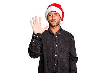 Young caucasian man celebrating Christmas wearing a santa hat isolated smiling cheerful showing number five with fingers.