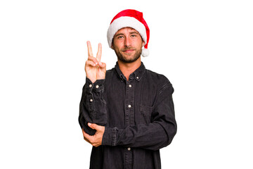 Young caucasian man celebrating Christmas wearing a santa hat isolated showing number two with fingers.