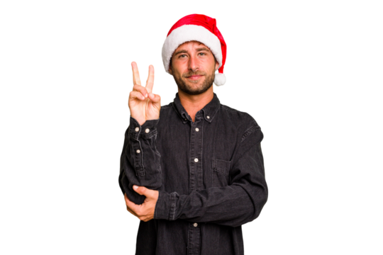 Young caucasian man celebrating Christmas wearing a santa hat isolated showing number two with fingers.