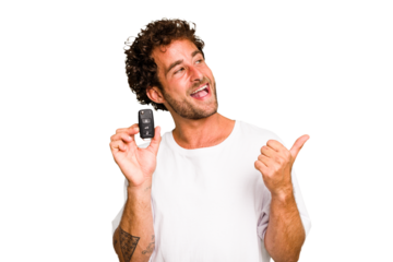 Young caucasian man holding car keys isolated points with thumb finger away, laughing and carefree.