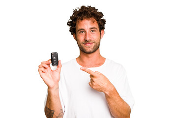 Young caucasian man holding car keys isolated smiling and pointing aside, showing something at...