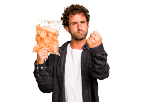 Young caucasian man holding crips isolated showing fist to camera, aggressive facial expression.
