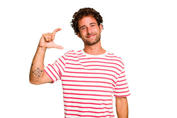Young caucasian curly hair man isolated Young caucasian man with curly hair isolated holding something little with forefingers, smiling and confident.