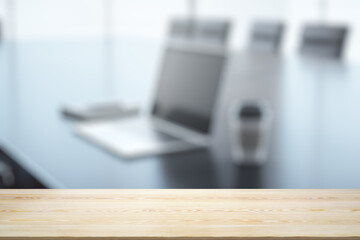 Empty wooden office table with light sunny workplace with computer on background, mock up