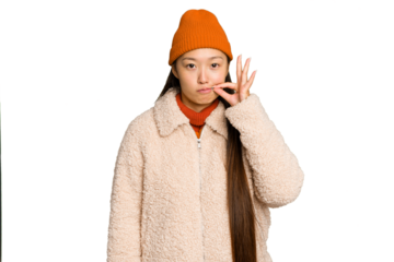 Young asian woman wearing winter clothes isolated on green chroma background with fingers on lips keeping a secret.