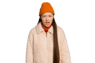 Young asian woman wearing winter clothes isolated on green chroma background screaming very angry and aggressive.