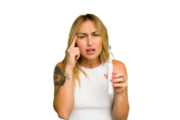 Young caucasian woman holding electric toothbrush isolated on green chroma background showing a disappointment gesture with forefinger.