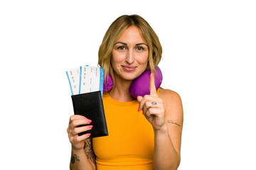 Young caucasian woman with inflatable travel pillow holding passport isolated on green chroma background showing number one with finger.