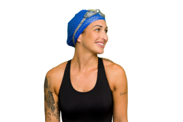 Young caucasian swimmer woman isolated on green chroma background looks aside smiling, cheerful and pleasant.