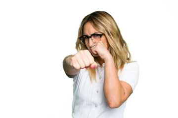 Young caucasian woman isolated on green chroma background throwing a punch, anger, fighting due to an argument, boxing.