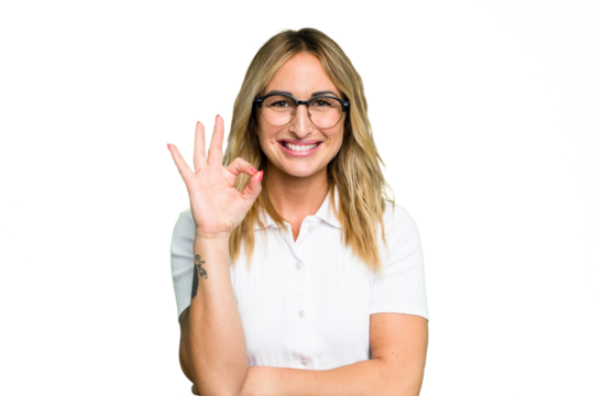 Young caucasian woman isolated on green chroma background winks an eye and holds an okay gesture with hand.