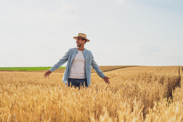 Naklejka na ściany i meble Happy farmer is standing in his growing wheat field. 