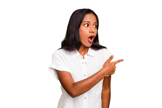 Young Indian woman isolated points with thumb finger away, laughing and carefree.