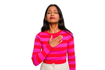Young Indian woman isolated taking an oath, putting hand on chest.