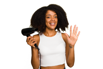 Young African American woman holding a hairdryer isolated smiling cheerful showing number five with fingers.